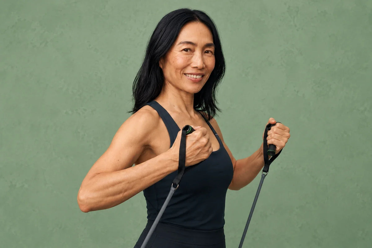 Mature Asian woman in dark training clothes holding resistance-band handles